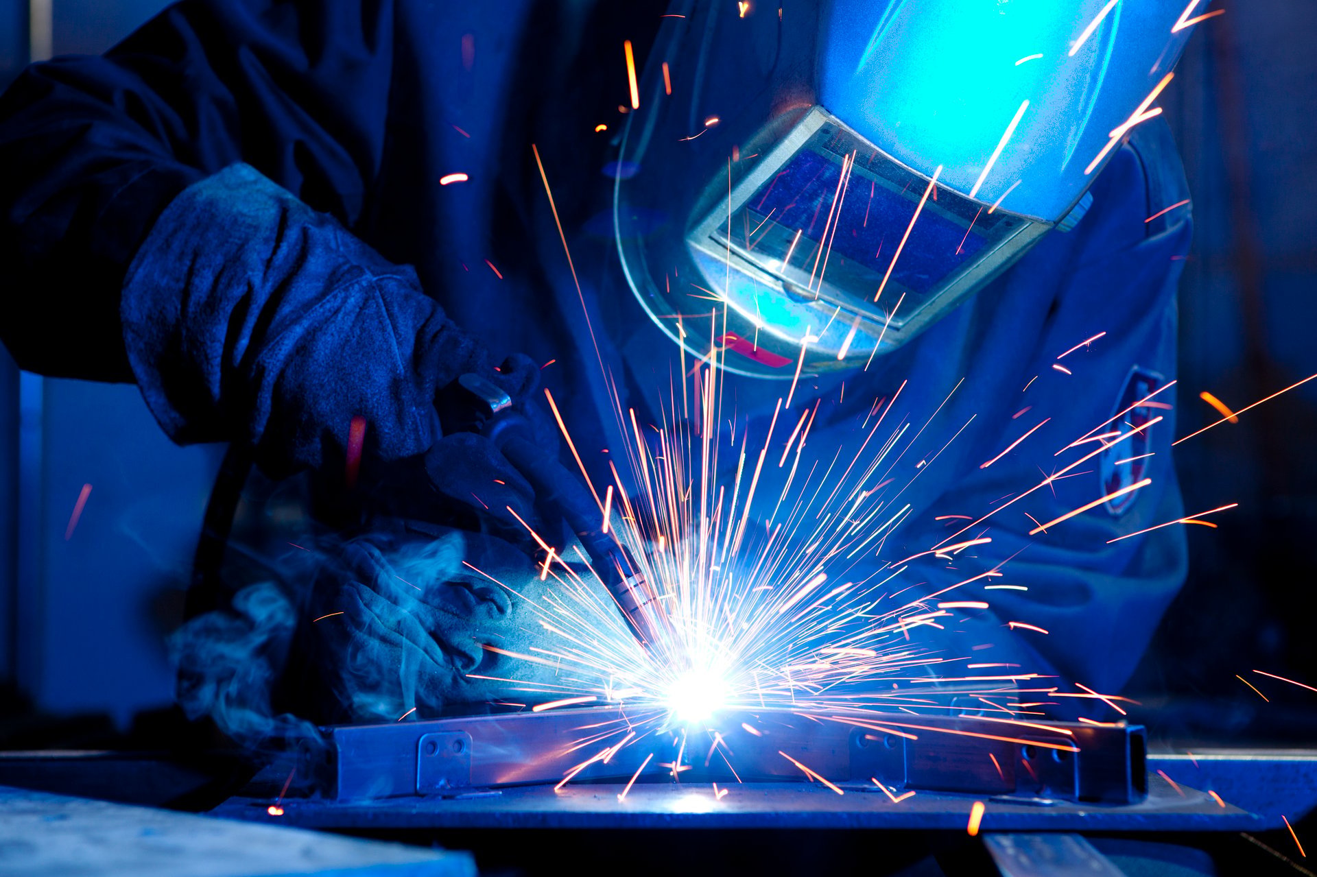 Steel erector welding structural steel in industrial setting
