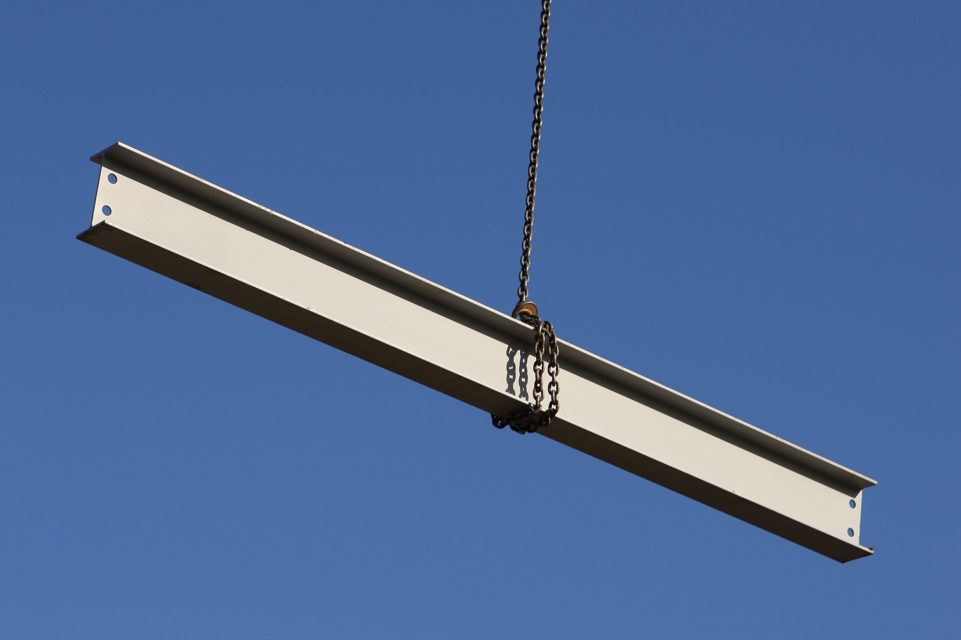 Steel girder swinging from crane on construction site